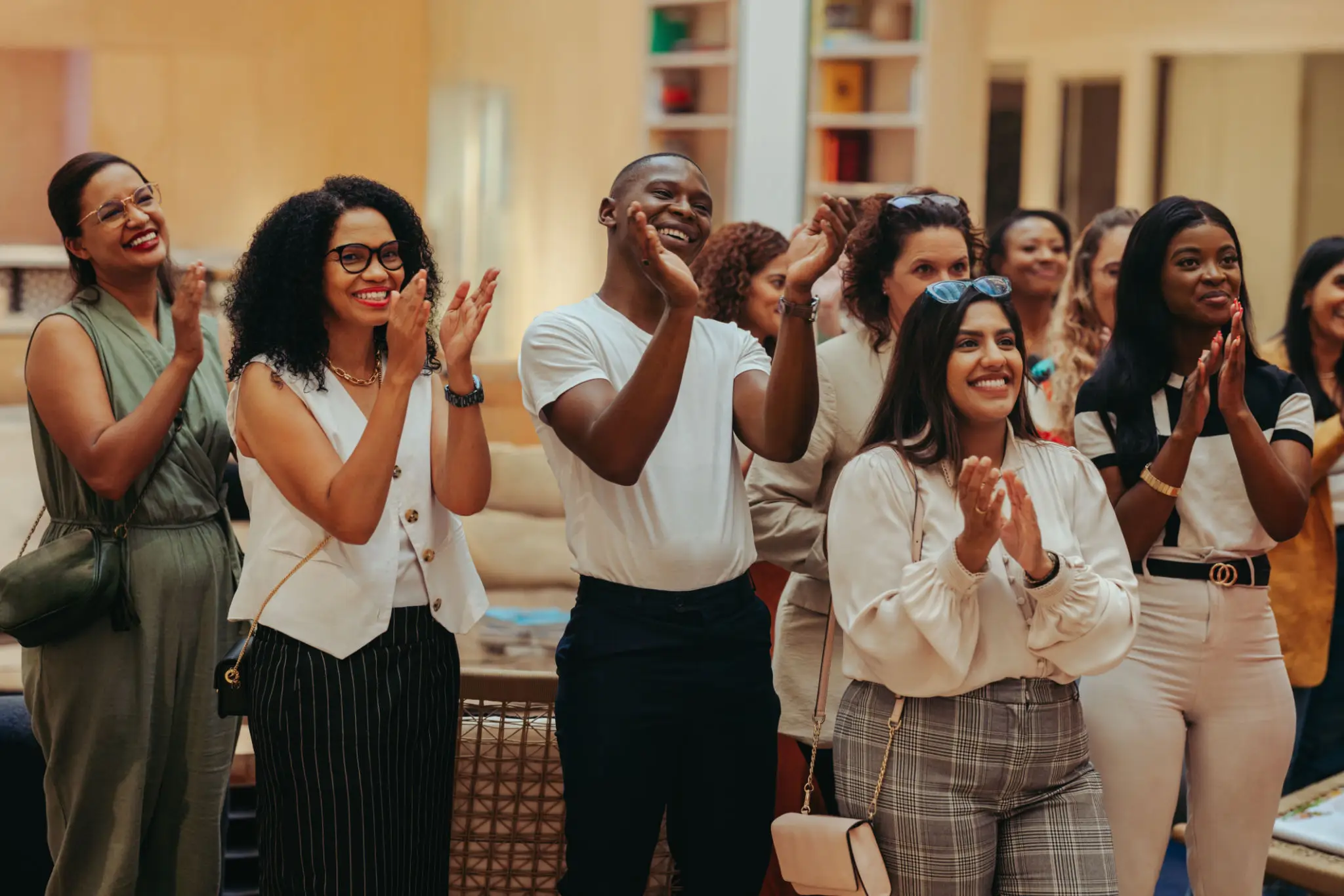 A diverse group of colleagues clapping and smiling in an office.